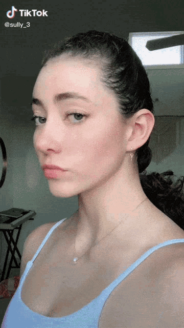 a woman in a blue tank top has a tiktok watermark on her face