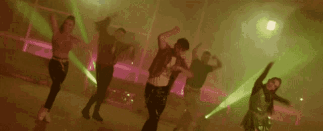 a group of people are dancing in a dark room with smoke coming out of the walls .