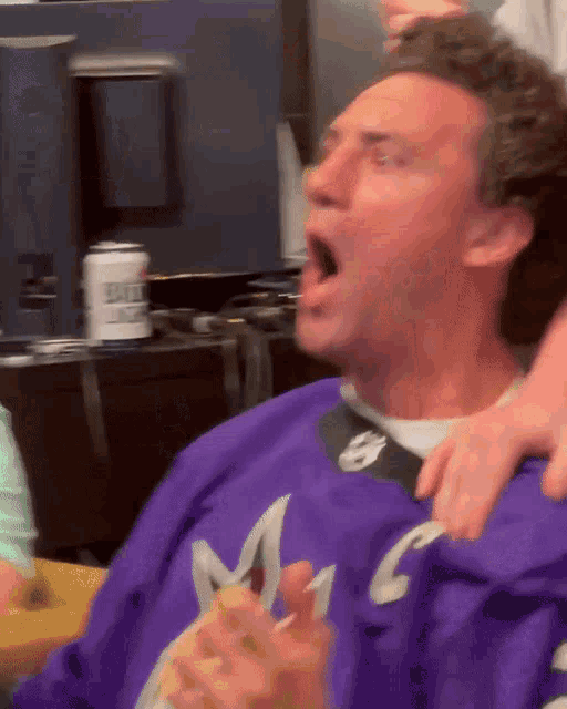 a man in a purple sweater with the letter m on it