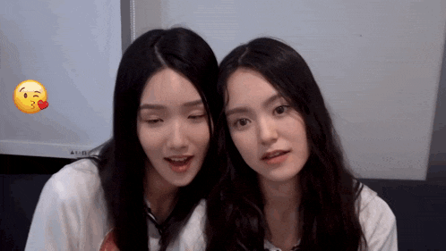 a couple of girls are standing next to each other with a smiley face behind them