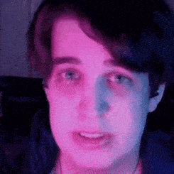 a close up of a person 's face with a purple and blue light behind them .