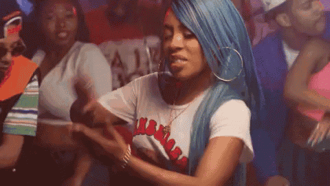 a woman with blue hair and hoop earrings is dancing in a crowd of people