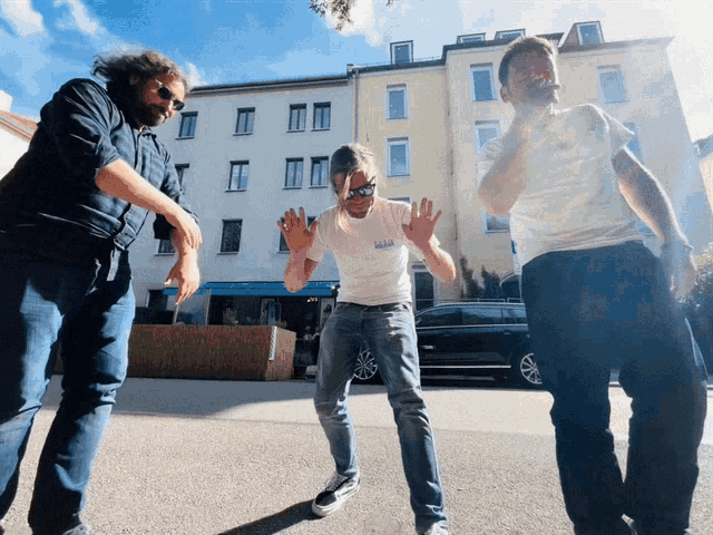 a man wearing a t-shirt that says ' supreme ' on it stands in front of two other men