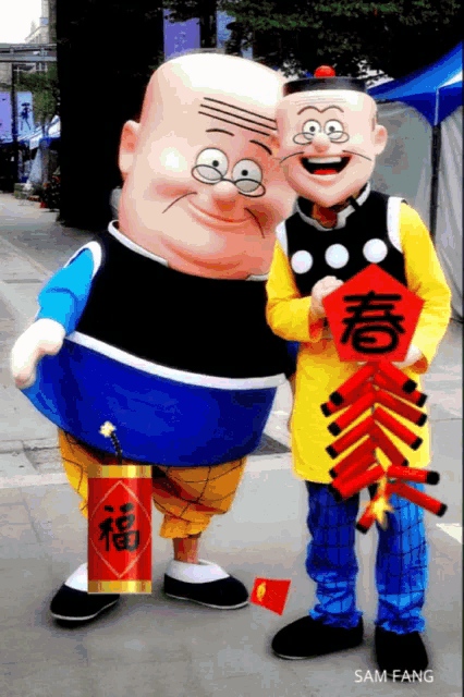 two mascots are standing next to each other and one has a red sign that says sam fang on it