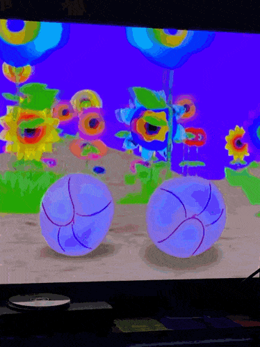 two blue balls are sitting in front of a bunch of sunflowers