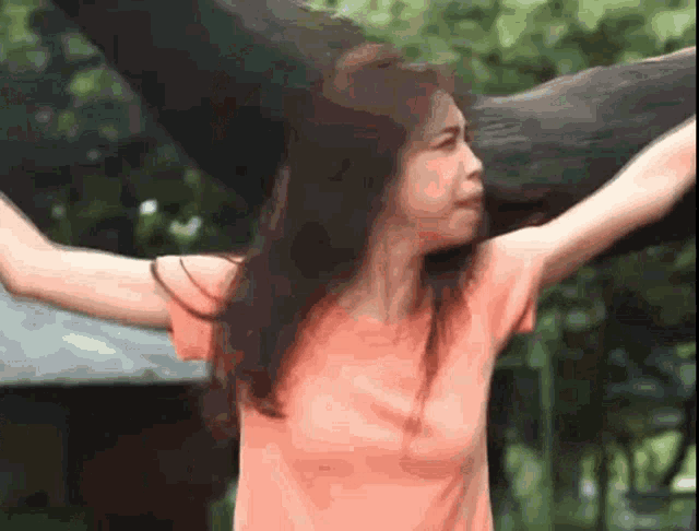 a woman in a pink shirt is holding an elephant 's head .