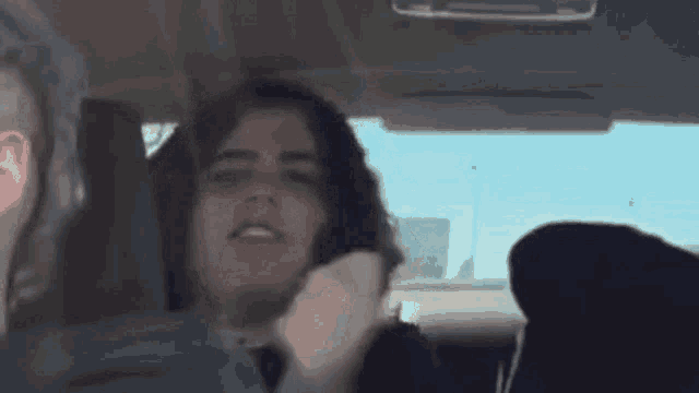 a woman is sitting in the driver 's seat of a car with her eyes closed