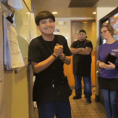 a man in a black shirt is clapping his hands in a restaurant