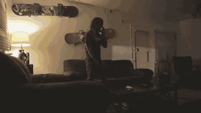 a person standing in a living room with snowboards on the wall including one that says jms
