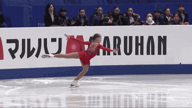 a woman ice skating in front of a banner that says maruhan