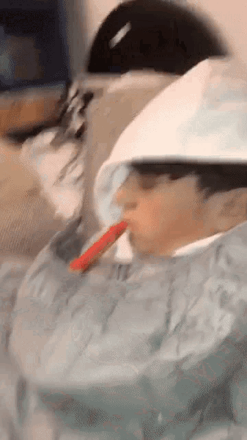 a person wearing a cowboy hat is drinking from a cup .