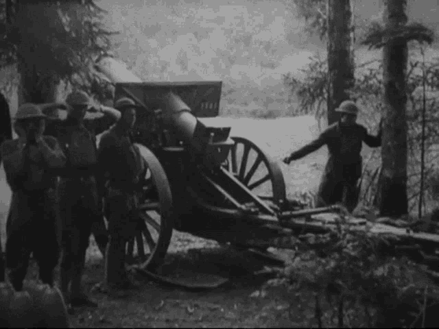 a black and white photo of soldiers loading a cannon into a field