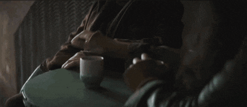 a man is sitting on a couch with a cup of coffee on a table .