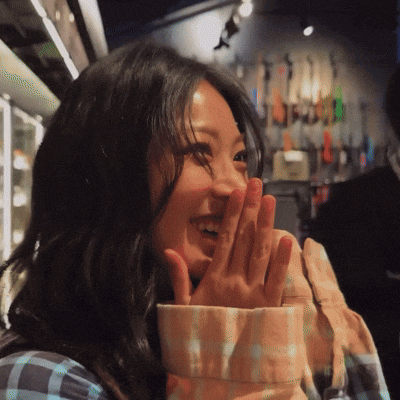 a woman covering her mouth with her hands in front of a guitar wall