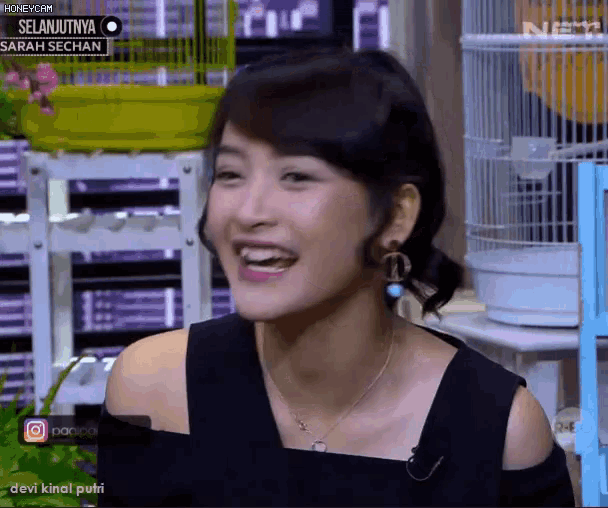 a woman is smiling in front of a sign that says selanjutnya