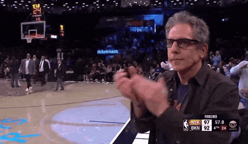 a man applauds during a basketball game with the score at 97-92
