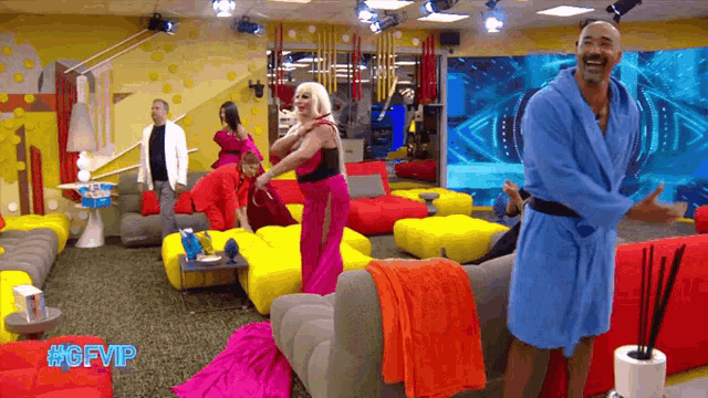 a man in a blue robe is standing in a living room with a #gfvip sticker