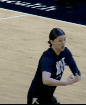 a woman wearing a shirt that says ' ucsd ' on it stands on a basketball court