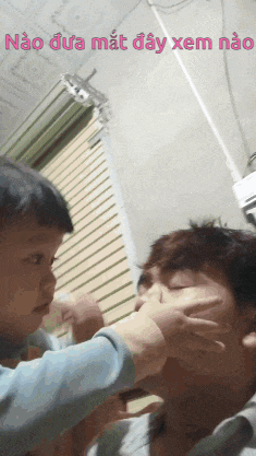 a little boy is putting his hand on a man 's face with the words nao dua mat day xem nao written above him