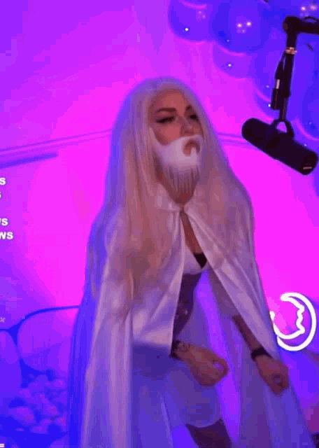 a woman in a white robe with a beard is standing in front of a neon sign that says on