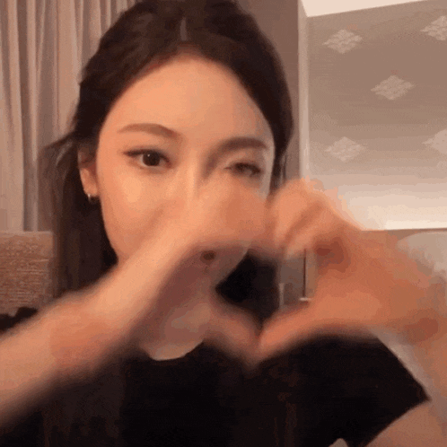 a woman is making a heart with her hands