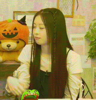 a woman wearing a pumpkin hat is sitting in front of a stuffed animal .