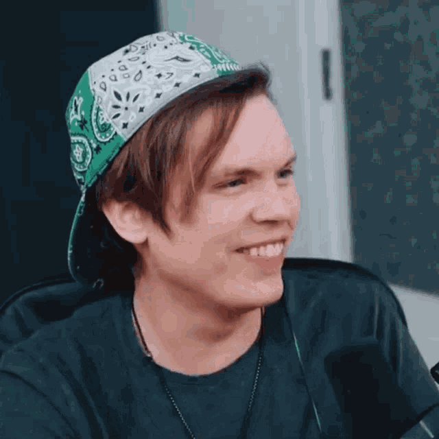 a young man wearing a green bandana and a baseball cap