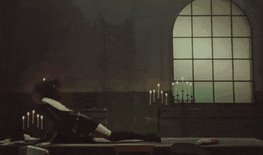 a woman is laying on a table in front of a window with candles