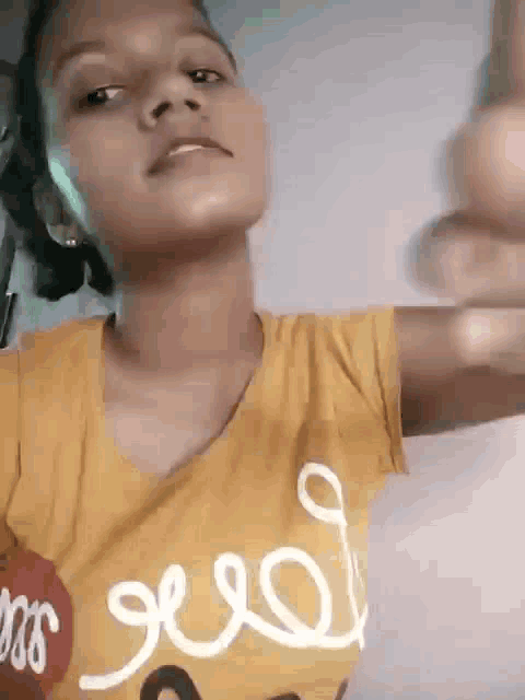 a young girl in a yellow shirt is giving a thumbs up