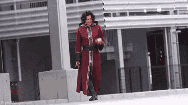 a man in a red coat and black boots is walking down a street .