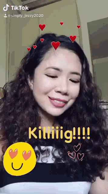 a woman with curly hair is smiling with hearts around her head and the words killiig !!! on the bottom