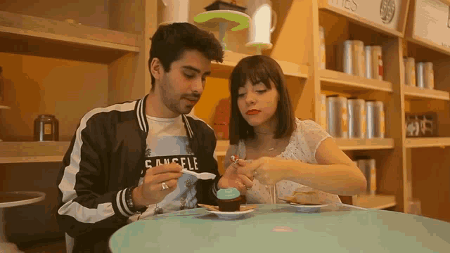 a man and a woman are sitting at a table and the man is wearing a shirt that says angels