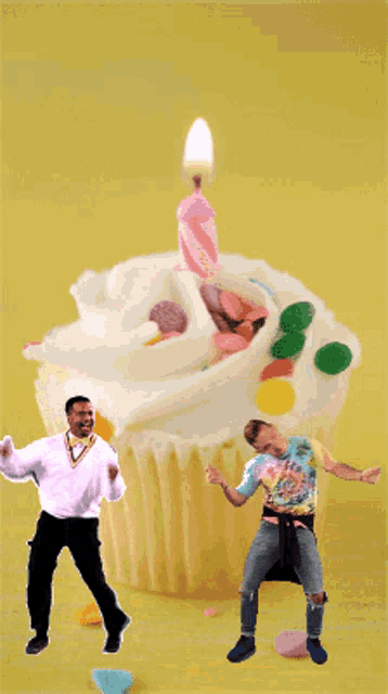 two men are dancing in front of a large cupcake with a candle on top