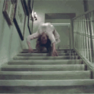a woman is doing a handstand on the stairs in a room .