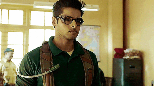 a young man wearing glasses and a green shirt