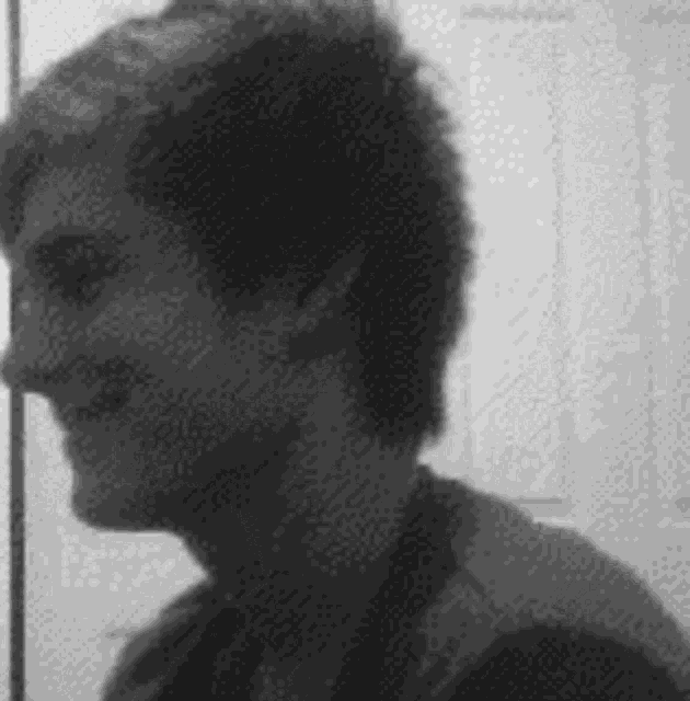 a black and white photo of a man standing in front of a mirror .
