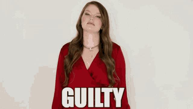 a woman in a red dress is standing in front of a white wall with the word guilty on it .
