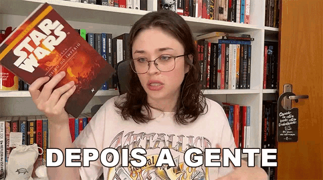 a woman is holding a star wars book in front of a bookshelf