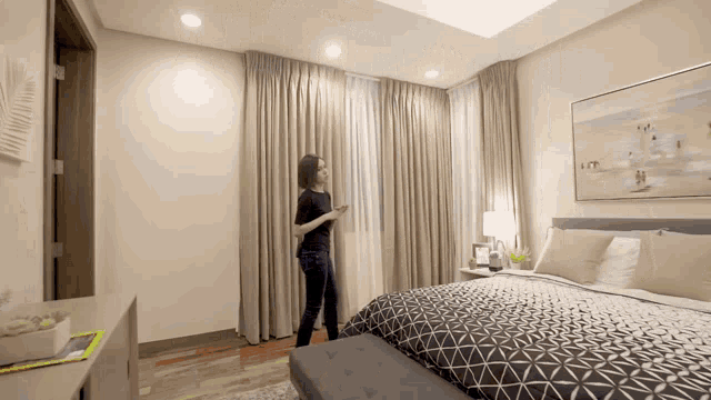 a woman in a black shirt is standing in a bedroom