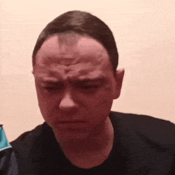 a man with a bald head is making a funny face while looking at the camera .