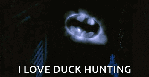 a batman logo is glowing in the dark with the words `` i love duck hunting '' below it .