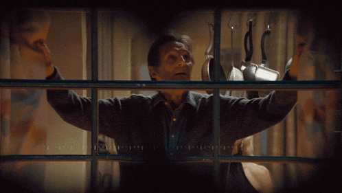 a man looking out a window with a clock on the wall that shows the time as 10:11