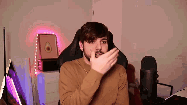 a man with a beard is sitting in front of a microphone covering his mouth