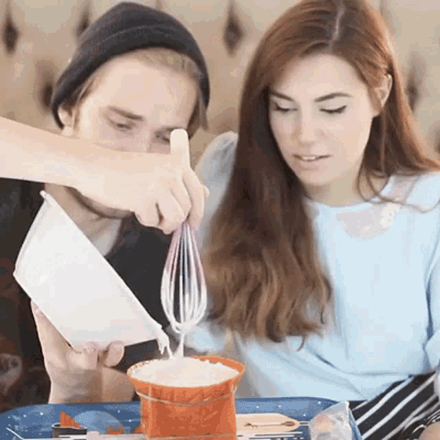 a man is pouring milk into a bucket while a woman watches ..