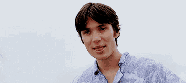 a close up of a young man 's face with a blue shirt on