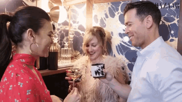 a man and two women are toasting with drinks in front of a wall that says river