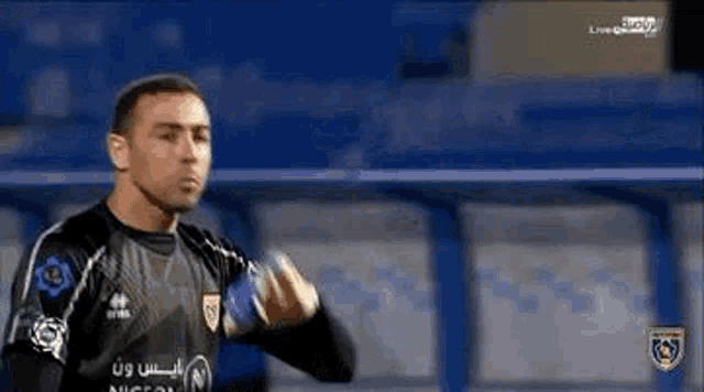a soccer goalie is standing on a field wearing gloves and a jersey .