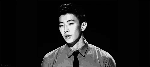 a black and white photo of a young man wearing a tie and a shirt .