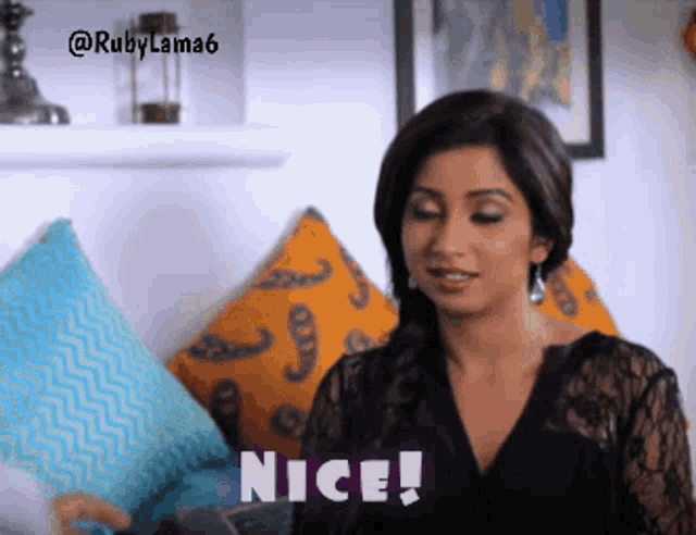 a woman is sitting on a couch with pillows and says " nice "