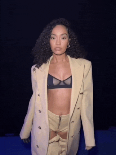 a woman in a bra and a suit is walking down a runway .